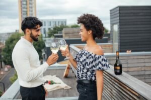 A happy couple toasting with wine on a rooftop, enjoying a lovely outdoor moment.