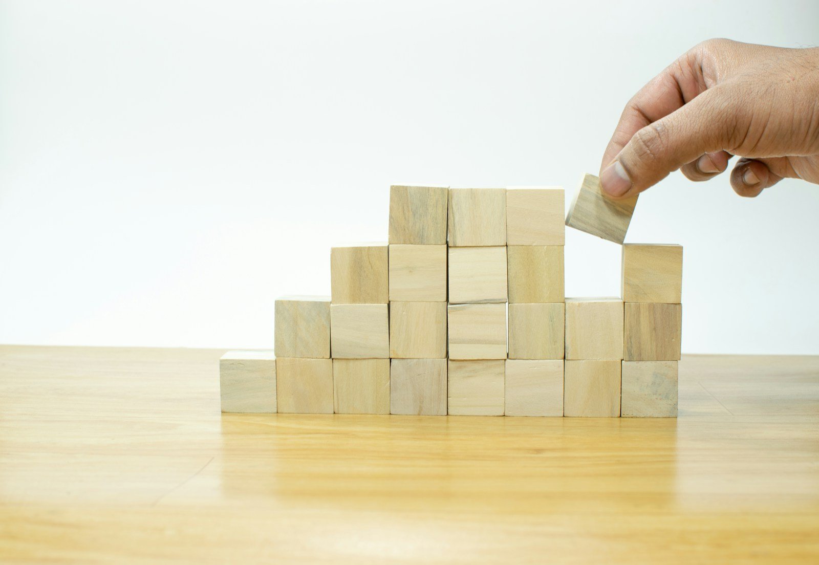 A person placing a block into a pile of wooden blocks, job, resume, work, unemployment, growth